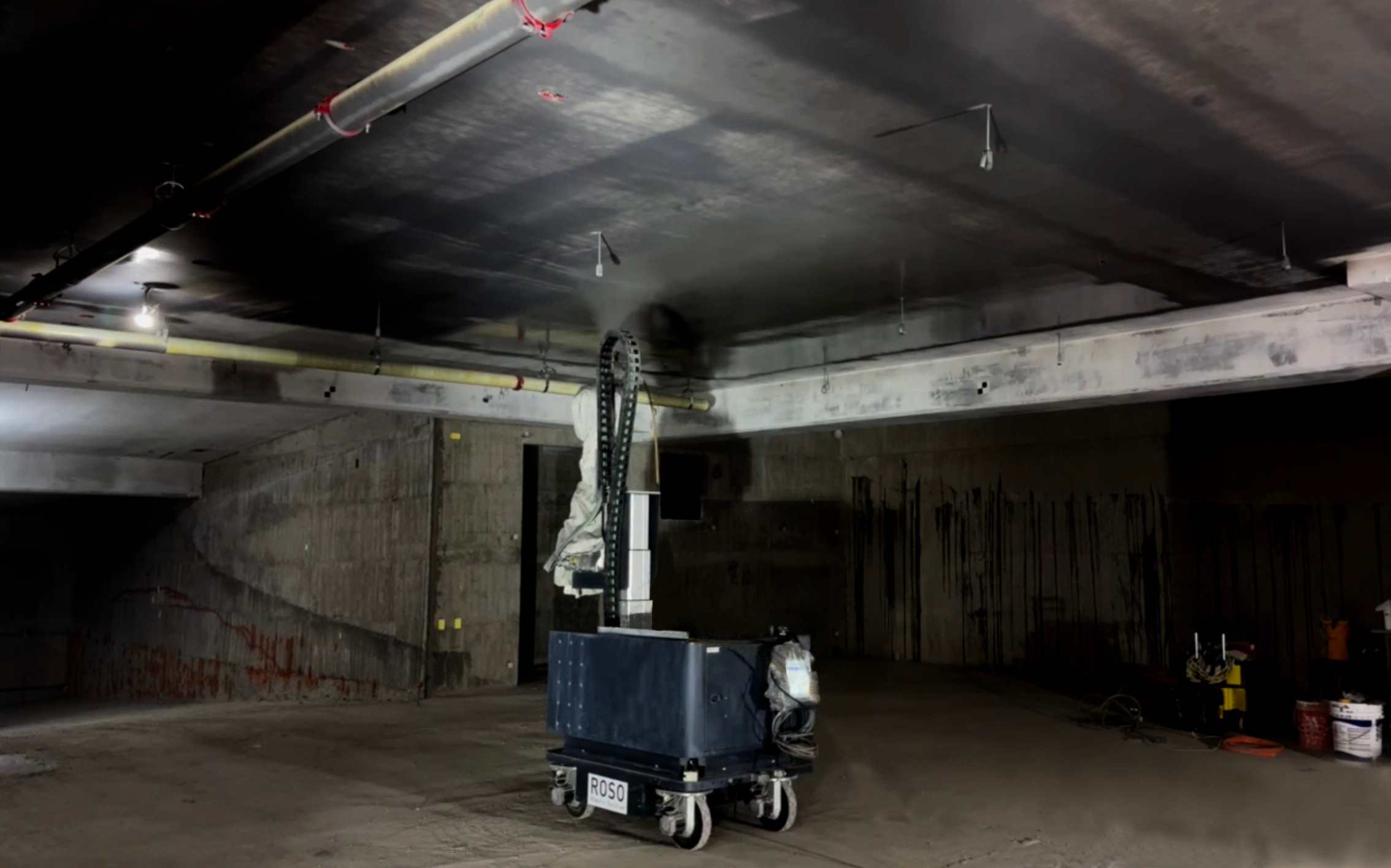 ROSO construction robot reaching toward a ceiling in an unfinished interior.