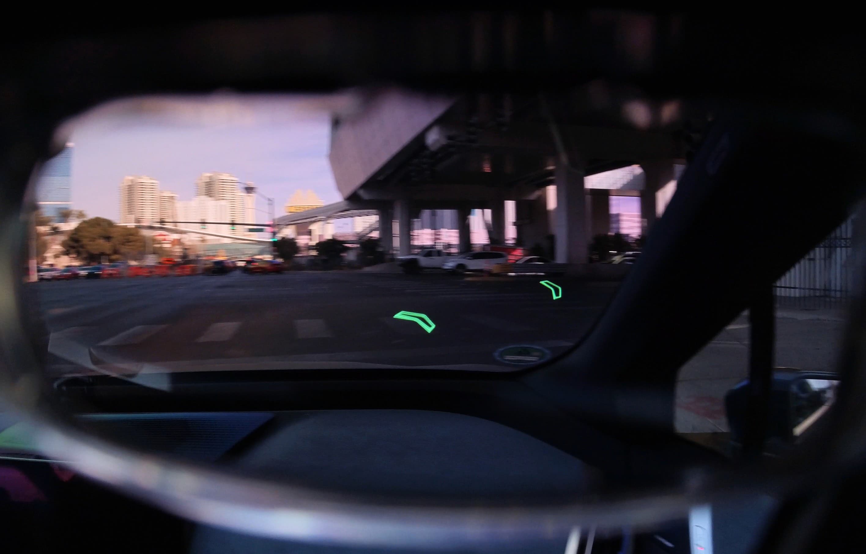 First-person AR navigation chevrons viewed through glasses inside a BMW.